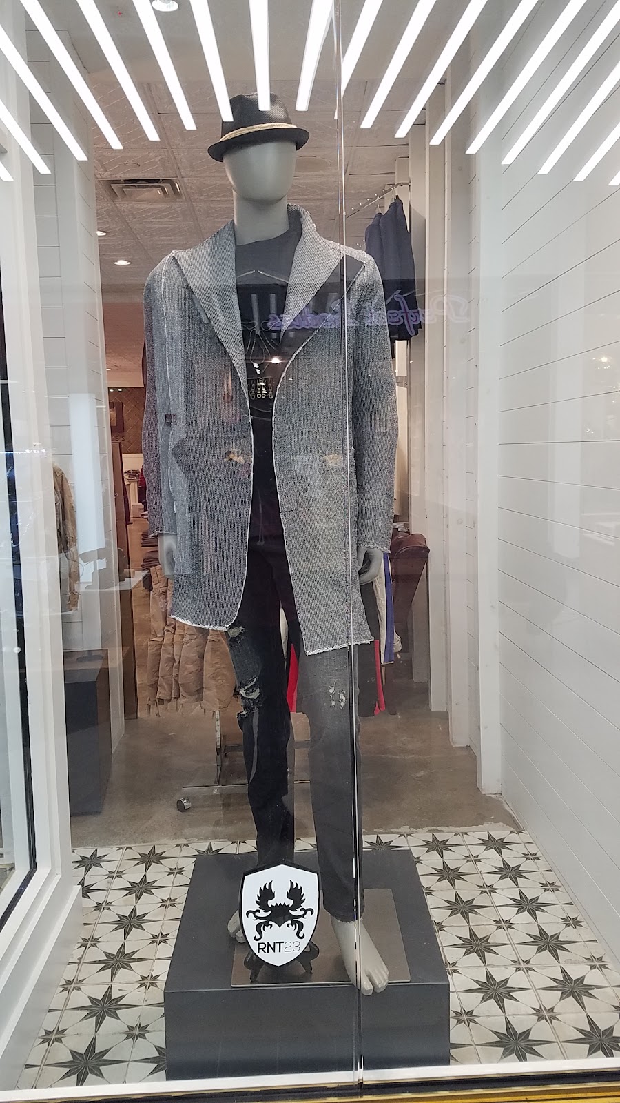 Editorial fashion model in a tailored black coat and bright scarf, lit in deep teal