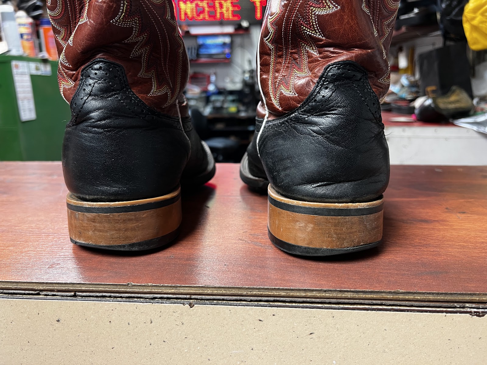 Shoe Repair orange sneaker held in a dark moody studio