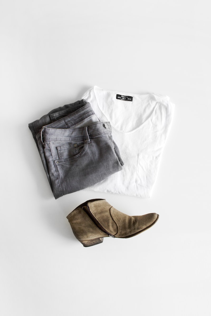 White boxy tee folded beside suede boots on a white surface